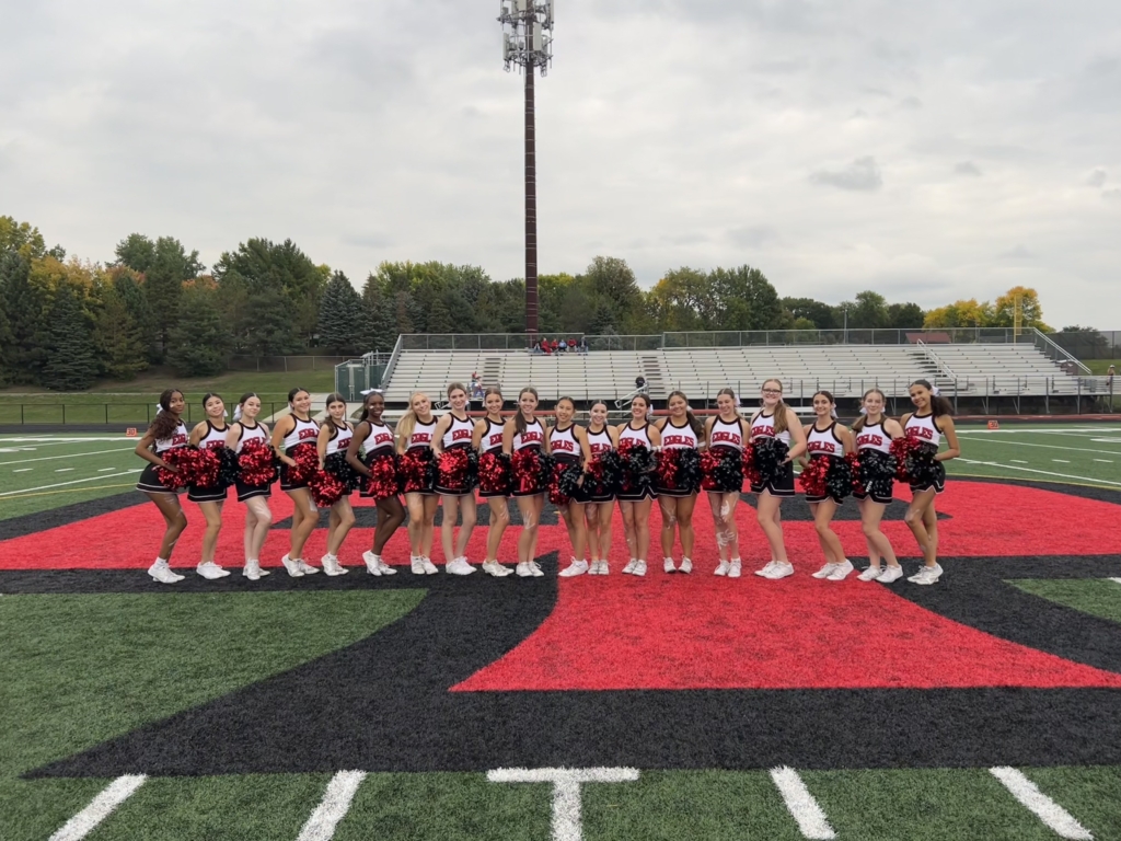 The cheer team from Eden Prairie High School (EPHS) posed for a portrait on a football field.