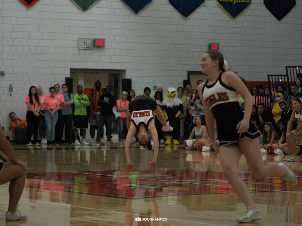 Eden Prairie High School (EPHS) cheerleader performs a backbend flip in gymnasium.